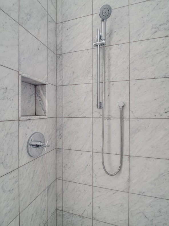 Modern inredning av ett mellanstort vit vitt badrum med dusch, med skåp i mörkt trä, en toalettstol med hel cisternkåpa, grå kakel, vita väggar, släta luckor, en dusch i en alkov, marmorkakel, ett undermonterad handfat, bänkskiva i akrylsten, med dusch som är öppen, marmorgolv och grått golv