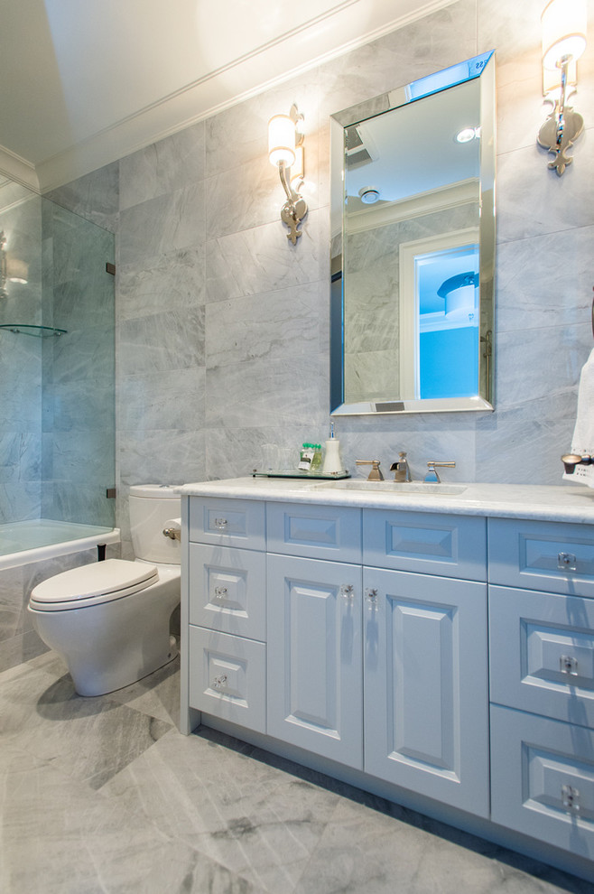 Cette photo montre une grande salle d'eau chic avec un lavabo encastré, des portes de placard blanches, un plan de toilette en marbre, une baignoire en alcôve, un combiné douche/baignoire, WC à poser, un carrelage gris, un mur gris et un sol en ardoise.