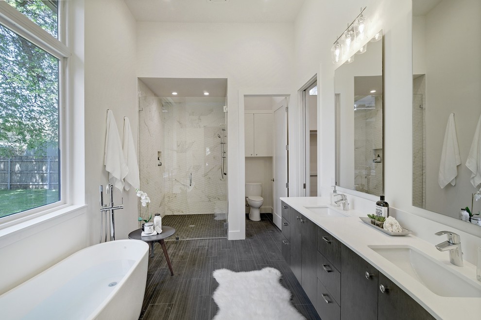 Design ideas for a large ensuite bathroom in Austin with brown cabinets, a freestanding bath, a walk-in shower, a one-piece toilet, white tiles, white walls, dark hardwood flooring, a submerged sink, brown floors, a hinged door, white worktops, porcelain tiles and engineered stone worktops.