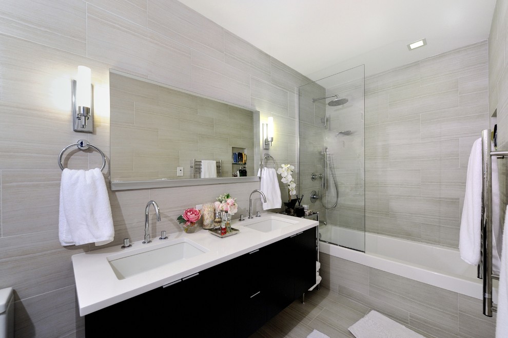 Bathroom - mid-sized contemporary gray tile bathroom idea in New York with an integrated sink, flat-panel cabinets, black cabinets, solid surface countertops, a two-piece toilet and beige walls