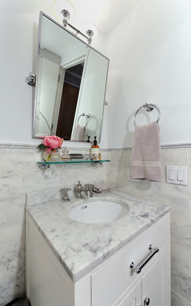 Immagine di una piccola stanza da bagno minimal con lavabo integrato, ante con bugna sagomata, ante bianche, top in marmo, WC a due pezzi, piastrelle bianche, pareti grigie e parquet scuro