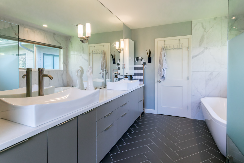 Modernes Badezimmer En Suite mit flächenbündigen Schrankfronten, grauen Schränken, freistehender Badewanne, Duschnische, schwarz-weißen Fliesen, grauen Fliesen, Marmorfliesen, Aufsatzwaschbecken, grauem Boden und Falttür-Duschabtrennung in Austin
