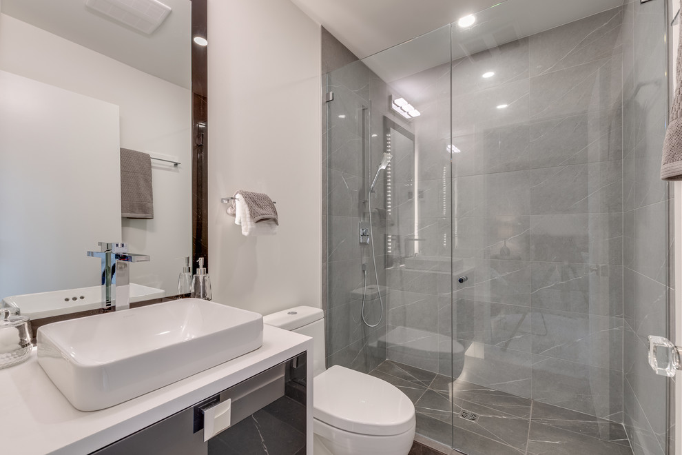 Пример оригинального дизайна: главная ванная комната в стиле модернизм с стеклянными фасадами, белыми фасадами, отдельно стоящей ванной, открытым душем, унитазом-моноблоком, белой плиткой, каменной плиткой, белыми стенами, мраморным полом, настольной раковиной, столешницей из искусственного кварца, белым полом, душем с распашными дверями и белой столешницей
