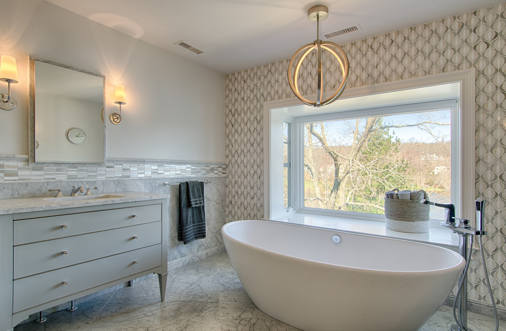 Пример оригинального дизайна: главная ванная комната среднего размера в стиле неоклассика (современная классика) с серыми фасадами, отдельно стоящей ванной, плиткой мозаикой, врезной раковиной, серыми стенами, мраморным полом, окном и плоскими фасадами