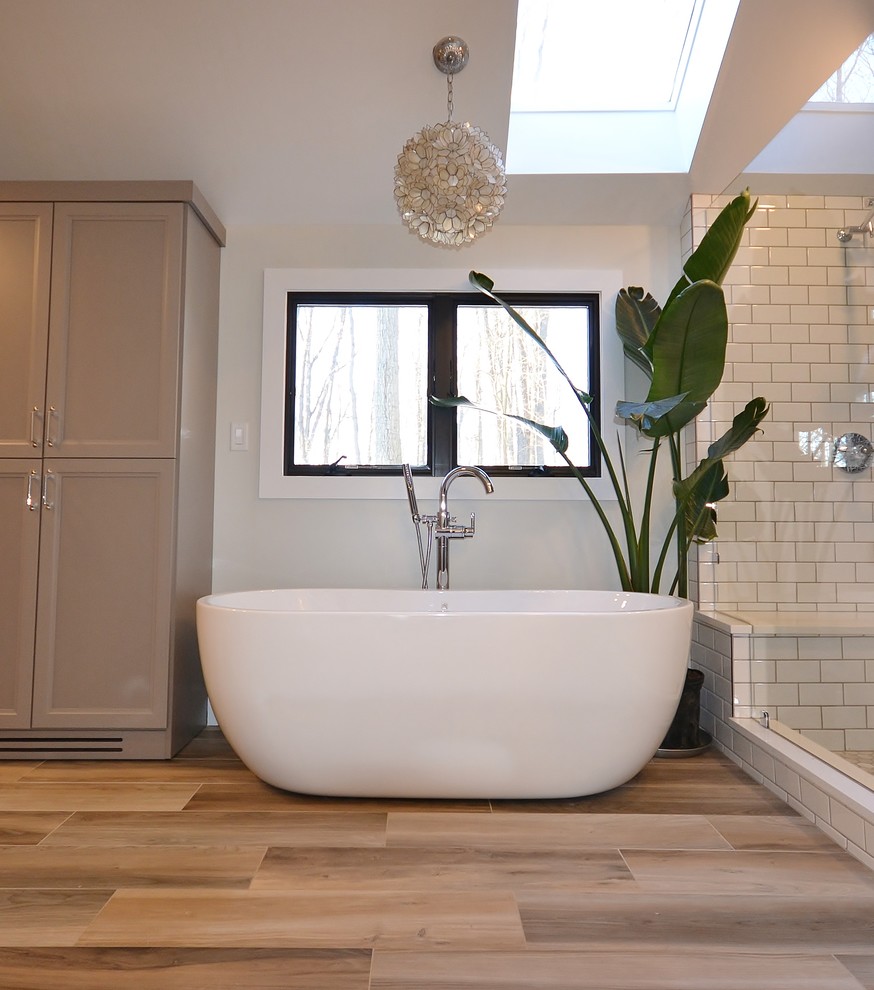 Inspiration for a large traditional ensuite bathroom in Philadelphia with shaker cabinets, distressed cabinets, a freestanding bath, a double shower, a one-piece toilet, multi-coloured tiles, metro tiles, white walls, medium hardwood flooring, a submerged sink, engineered stone worktops, brown floors, a hinged door and white worktops.