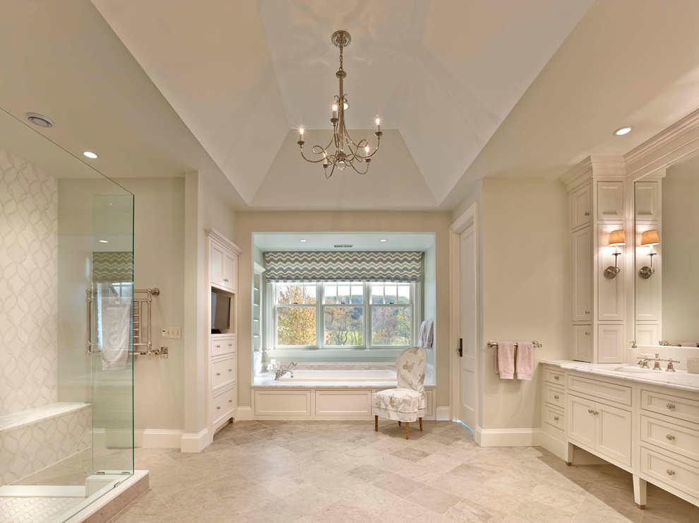 Klassisk inredning av ett mycket stort en-suite badrum, med luckor med infälld panel, vita skåp, ett platsbyggt badkar, en hörndusch, vit kakel, beige väggar, ett undermonterad handfat, marmorbänkskiva, beiget golv och dusch med gångjärnsdörr