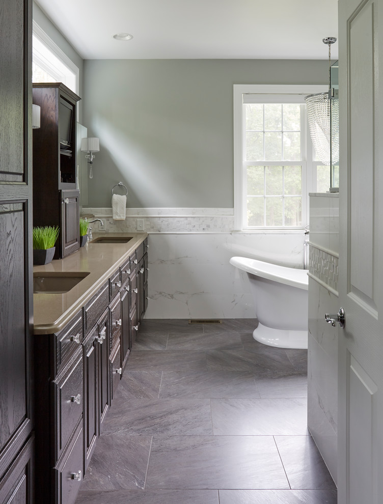 Design ideas for a large traditional ensuite bathroom in Philadelphia with raised-panel cabinets, brown cabinets, a freestanding bath, a built-in shower, a two-piece toilet, white tiles, porcelain tiles, grey walls, porcelain flooring, a submerged sink, engineered stone worktops, grey floors and a hinged door.
