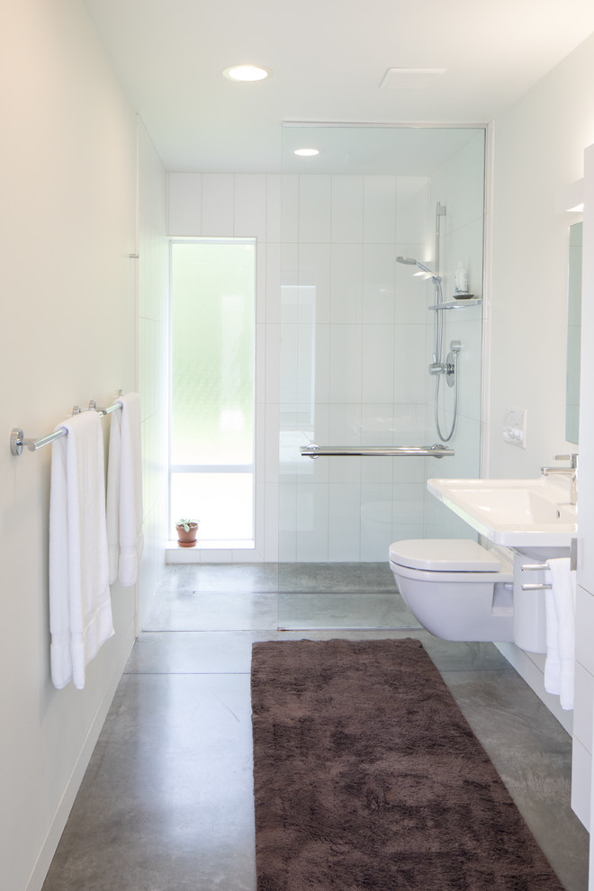 Foto de cuarto de baño principal minimalista de tamaño medio con ducha abierta, sanitario de pared, paredes blancas, suelo de cemento, lavabo suspendido, suelo gris y ducha abierta