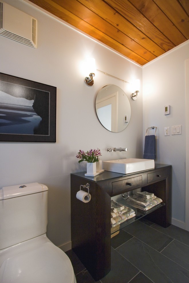 Inredning av ett modernt mellanstort badrum med dusch, med ett fristående handfat, möbel-liknande, skåp i mörkt trä, träbänkskiva, en dusch/badkar-kombination, en toalettstol med separat cisternkåpa, svart kakel, stenkakel, skiffergolv och grått golv