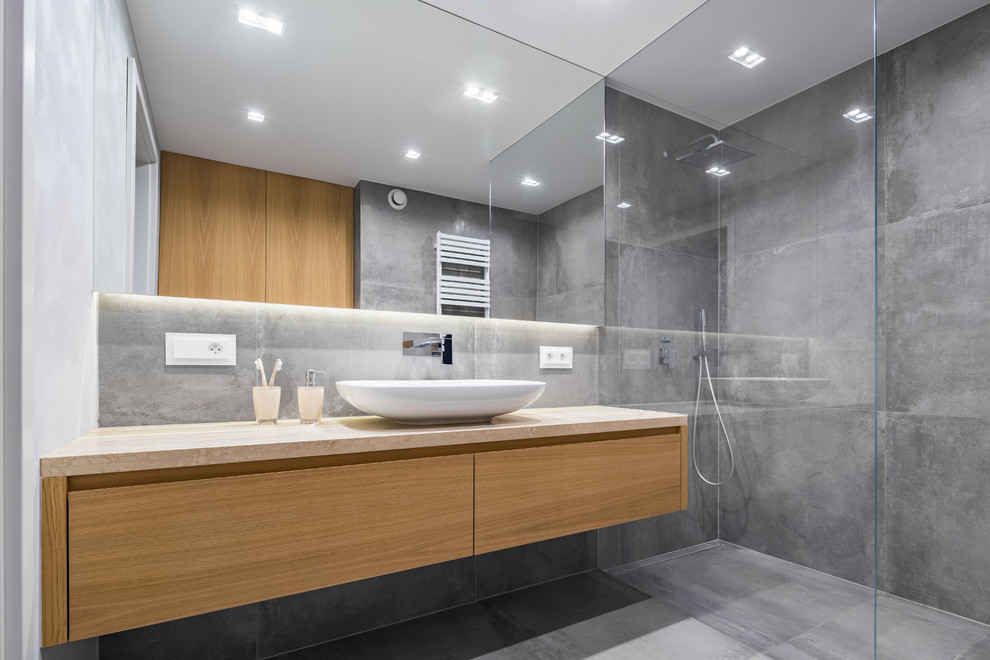 Стильный дизайн: главная ванная комната среднего размера в стиле модернизм с серой плиткой, керамической плиткой, серыми стенами, полом из цементной плитки, настольной раковиной, серым полом, душем с распашными дверями и бежевой столешницей - последний тренд