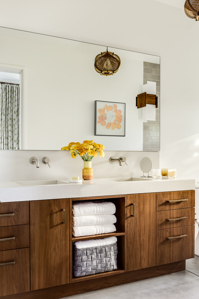 Foto di una stanza da bagno etnica con ante lisce, ante marroni, pareti bianche, pavimento in cemento, lavabo integrato e pavimento grigio