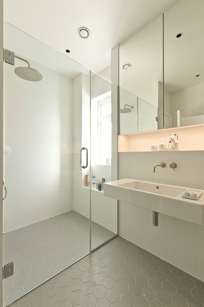 Свежая идея для дизайна: ванная комната в стиле модернизм с душем без бортиков, белой плиткой, подвесной раковиной, серым полом и душем с распашными дверями - отличное фото интерьера