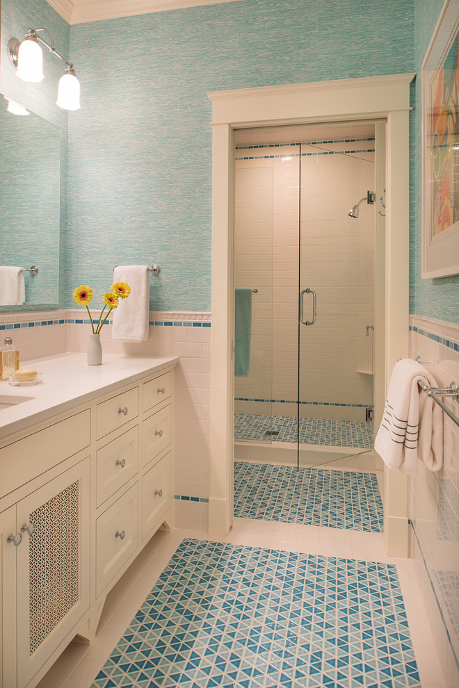 Maritim inredning av ett badrum med dusch, med skåp i shakerstil, vita skåp, en dusch i en alkov, blå kakel, vit kakel, blå väggar, mosaikgolv, ett undermonterad handfat och dusch med gångjärnsdörr