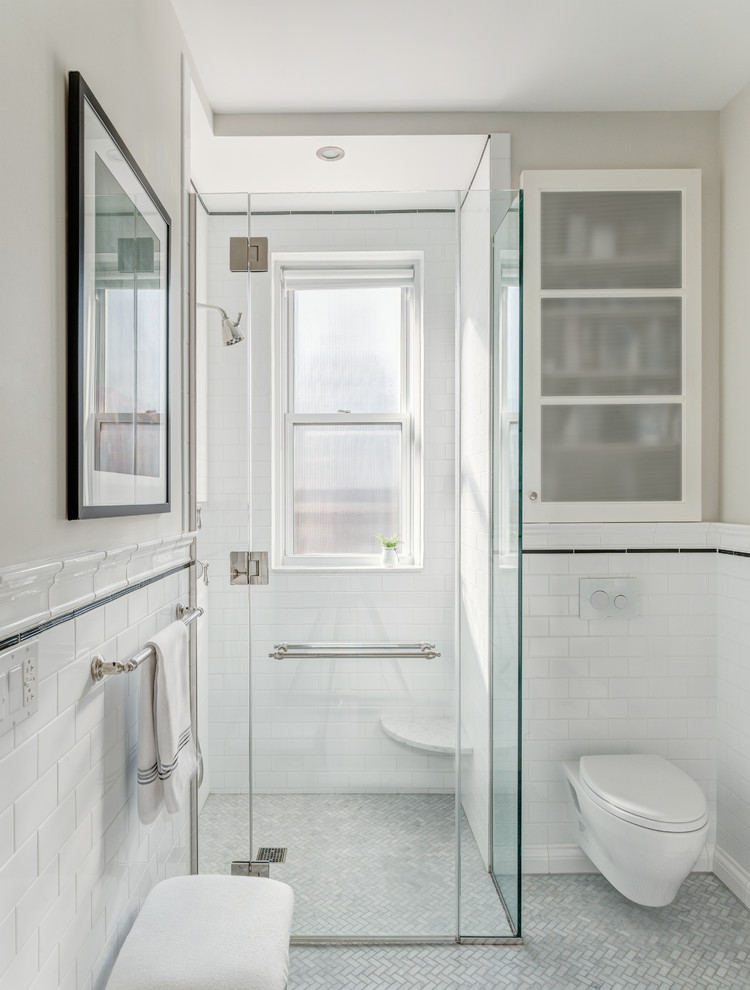Bild på ett mellanstort funkis badrum med dusch, med möbel-liknande, vita skåp, en hörndusch, en vägghängd toalettstol, vit kakel, tunnelbanekakel, beige väggar, marmorgolv, ett undermonterad handfat, marmorbänkskiva, grått golv och dusch med gångjärnsdörr