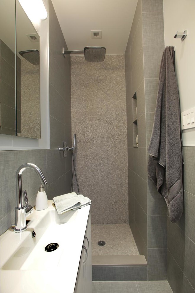 Idéer för små funkis badrum, med släta luckor, vita skåp, en dusch i en alkov, grå kakel, grå väggar, ett integrerad handfat, bänkskiva i akrylsten och en vägghängd toalettstol