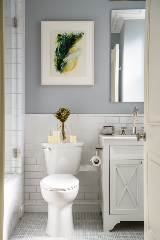 Пример оригинального дизайна: ванная комната среднего размера в классическом стиле с белыми фасадами, ванной в нише, душем над ванной, раздельным унитазом, белой плиткой, плиткой кабанчик, серыми стенами, полом из мозаичной плитки, врезной раковиной, мраморной столешницей, серым полом, душем с распашными дверями, серой столешницей и фасадами с утопленной филенкой