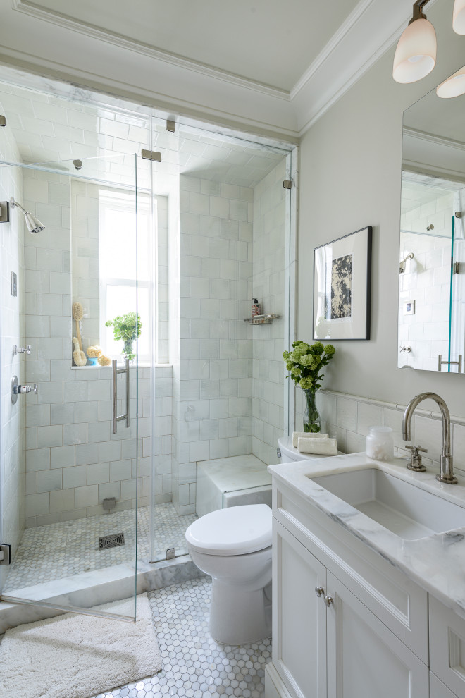 Alcove shower - mid-sized traditional master white tile and subway tile marble floor and gray floor alcove shower idea in New York with recessed-panel cabinets, white cabinets, a two-piece toilet, beige walls, an undermount sink, marble countertops, a hinged shower door and white countertops