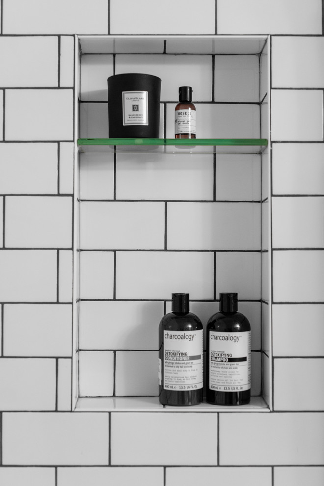 Пример оригинального дизайна: маленькая ванная комната в современном стиле с плоскими фасадами, светлыми деревянными фасадами, душем над ванной, раздельным унитазом, белой плиткой, плиткой кабанчик, белыми стенами, столешницей из искусственного камня, черным полом, шторкой для ванной, белой столешницей, ванной в нише, полом из мозаичной плитки, душевой кабиной и монолитной раковиной для на участке и в саду