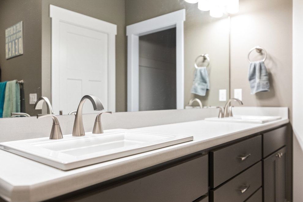 Modelo de cuarto de baño principal tradicional renovado de tamaño medio con armarios estilo shaker, puertas de armario grises, sanitario de una pieza, paredes grises, lavabo encastrado, encimera de laminado y encimeras blancas