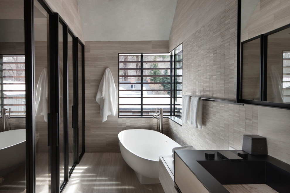 Esempio di una stanza da bagno contemporanea con vasca freestanding, pareti grigie, parquet chiaro e pavimento beige