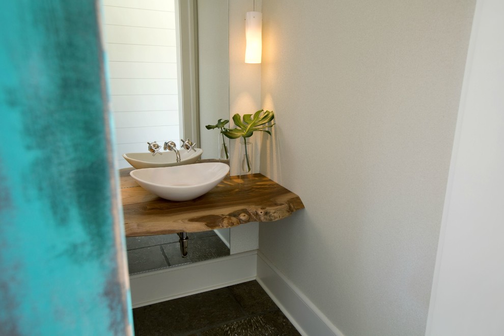 Cette image montre une petite salle d'eau minimaliste avec une vasque, un plan de toilette en bois et un mur blanc.