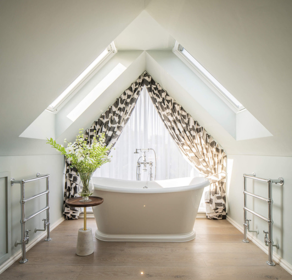 Photo of a classic ensuite bathroom in London with a freestanding bath, medium hardwood flooring and a vaulted ceiling.