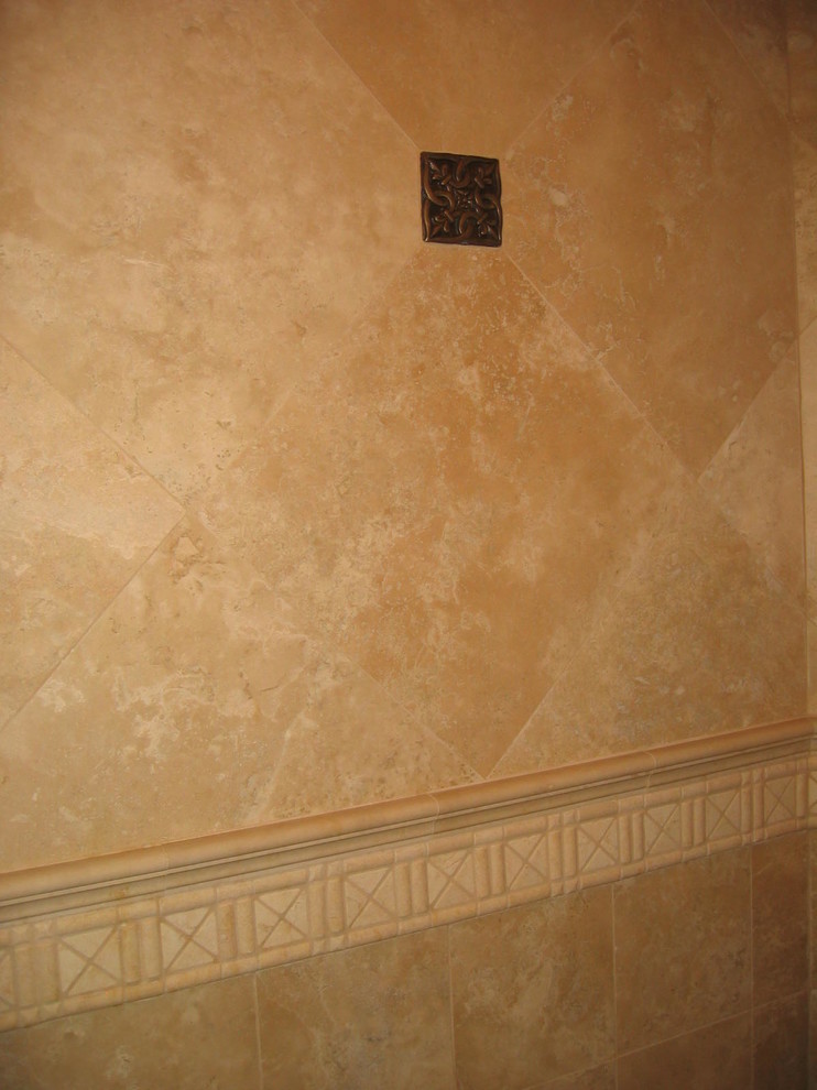 Klassisk inredning av ett badrum, med skåp i mörkt trä, ett platsbyggt badkar, stenkakel, blå väggar, travertin golv, ett undermonterad handfat och granitbänkskiva