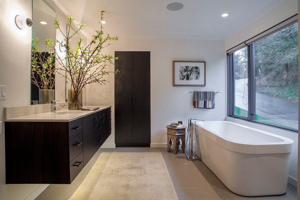Modelo de cuarto de baño actual con lavabo bajoencimera, armarios con paneles lisos, puertas de armario de madera en tonos medios y bañera exenta
