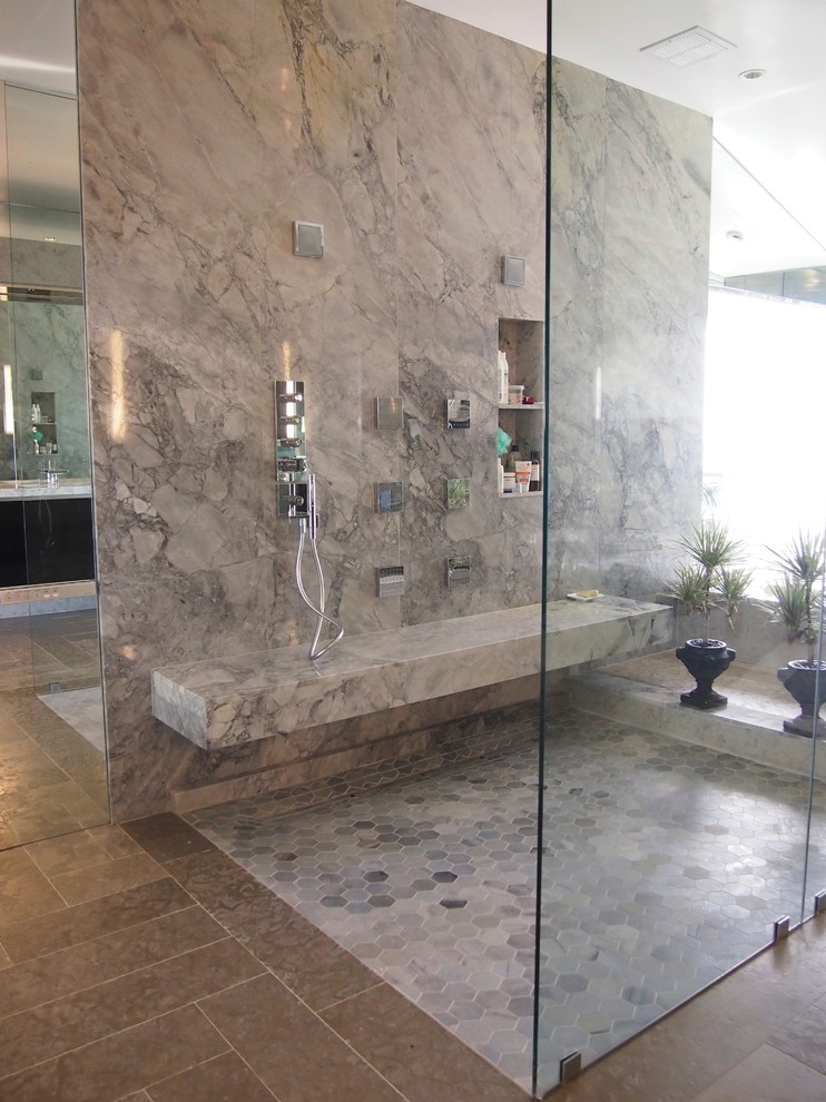 На фото: огромная главная ванная комната в стиле модернизм с плоскими фасадами, темными деревянными фасадами, полновстраиваемой ванной, душем без бортиков, инсталляцией, бежевой плиткой, плиткой из листового камня, бежевыми стенами, мраморным полом, врезной раковиной, столешницей из искусственного кварца, бежевым полом, открытым душем, белой столешницей, тумбой под две раковины, подвесной тумбой и любым потолком
