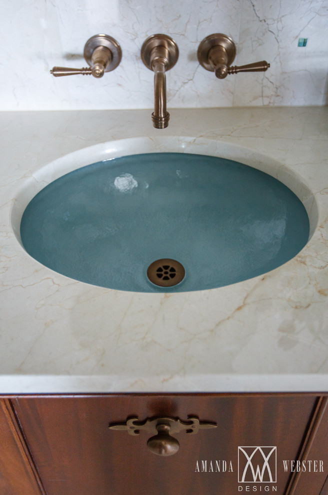 Immagine di una stanza da bagno tropicale con ante a filo, ante in legno scuro, lavabo sottopiano e top in marmo