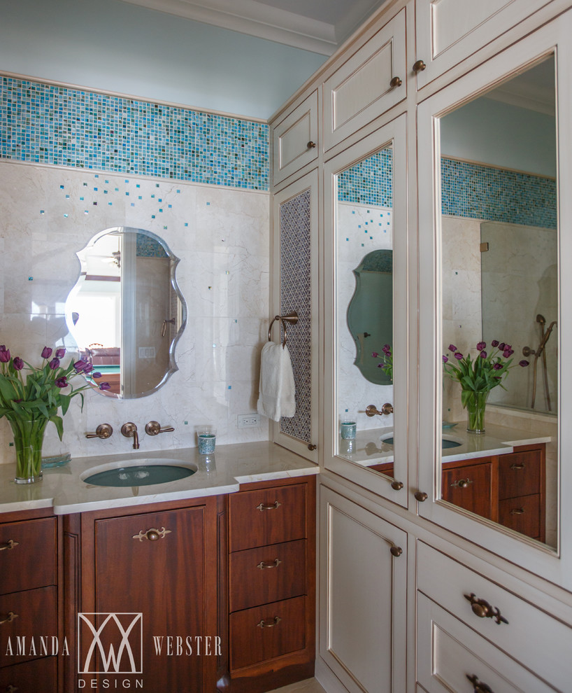 Bild på ett tropiskt badrum med dusch, med luckor med profilerade fronter, skåp i mellenmörkt trä, blå kakel, glaskakel, blå väggar, marmorgolv, ett undermonterad handfat och marmorbänkskiva