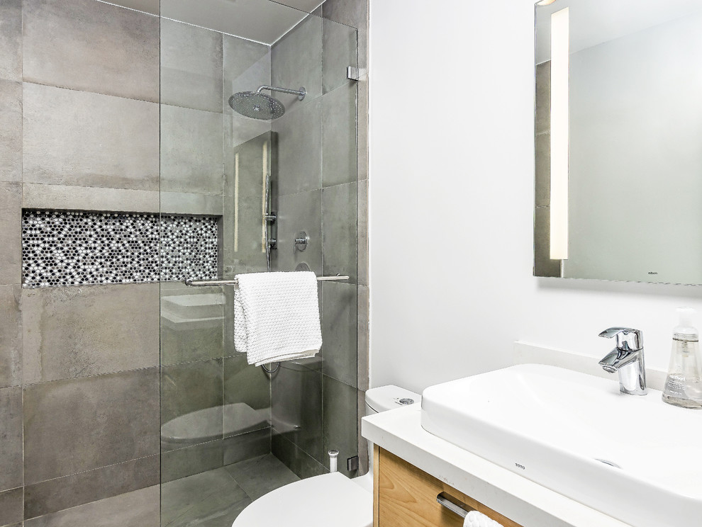 Mid-sized trendy master gray tile and porcelain tile porcelain tile bathroom photo in Los Angeles with flat-panel cabinets, light wood cabinets, a wall-mount toilet, white walls, a vessel sink, quartz countertops and white countertops