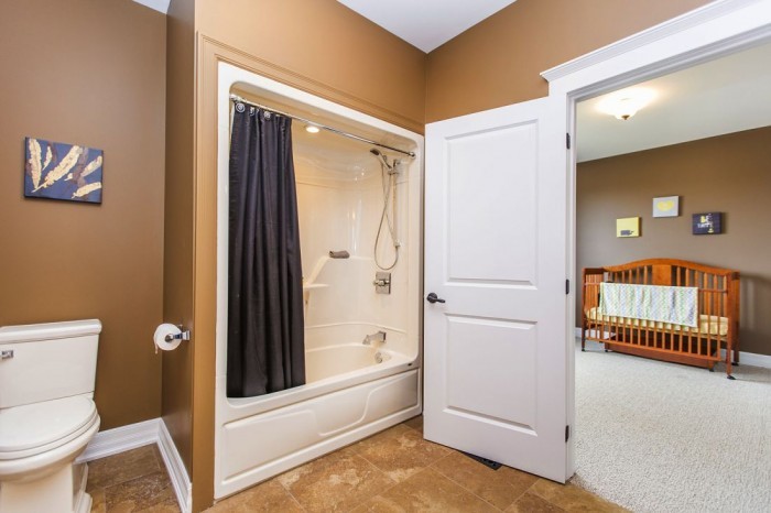 На фото: ванная комната в классическом стиле с темными деревянными фасадами, ванной в нише, душем в нише, раздельным унитазом, бежевой плиткой, коричневыми стенами, врезной раковиной и столешницей из гранита с