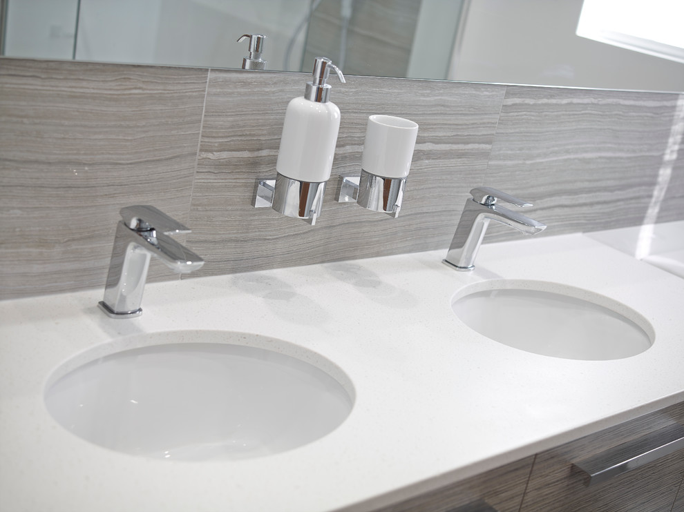 Inredning av ett modernt mellanstort badrum med dusch, med ett integrerad handfat, skåp i ljust trä, en hörndusch, en vägghängd toalettstol, grå kakel, vita väggar och klinkergolv i porslin