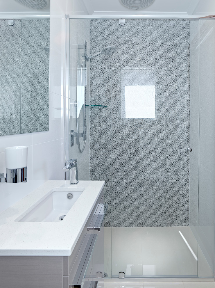 Esempio di una stanza da bagno con doccia minimal di medie dimensioni con lavabo integrato, ante in legno chiaro, doccia ad angolo, WC sospeso, piastrelle beige, pareti bianche e pavimento in gres porcellanato