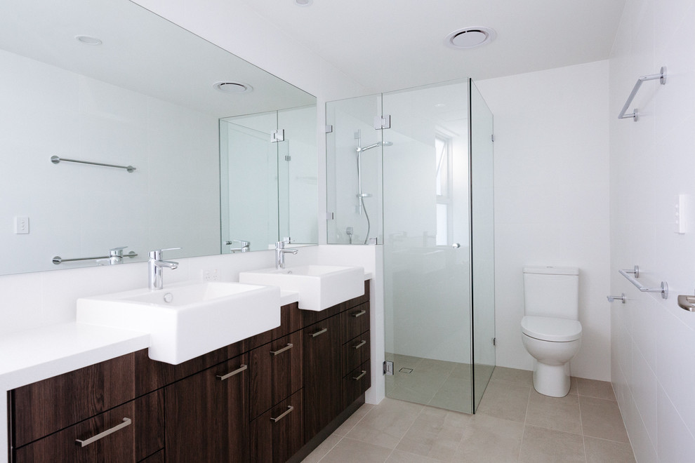 Example of a mid-sized minimalist kids' beige tile and porcelain tile porcelain tile alcove shower design in Perth with raised-panel cabinets, medium tone wood cabinets, a wall-mount toilet, white walls, an integrated sink and quartz countertops