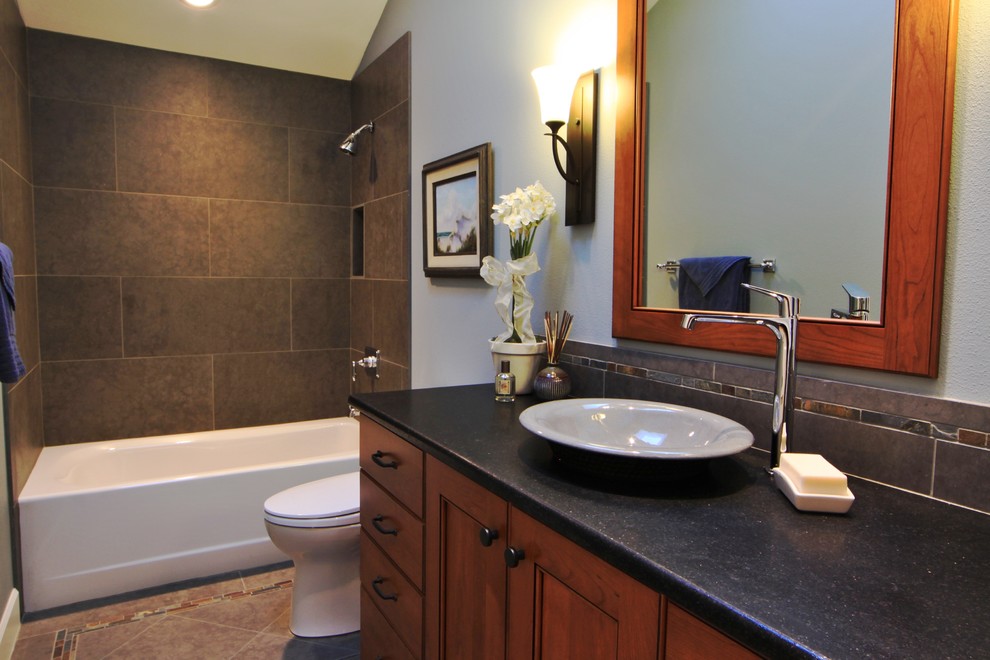 Mid-sized transitional beige tile and porcelain tile porcelain tile and beige floor bathroom photo in Portland with beaded inset cabinets, medium tone wood cabinets, a two-piece toilet, a vessel sink, granite countertops and black countertops