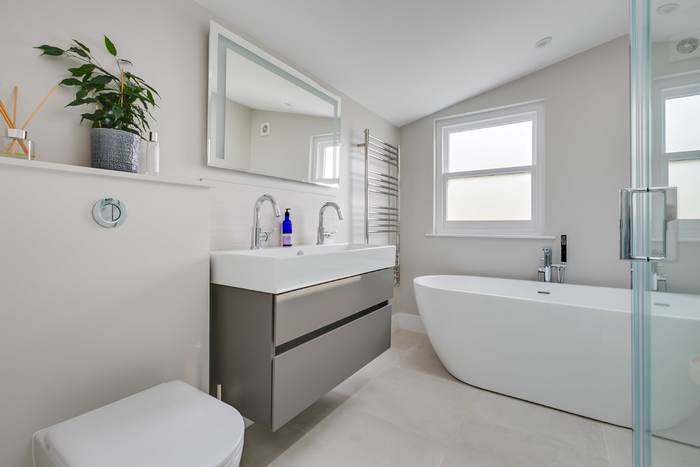 Large modern ensuite bathroom in London with a freestanding bath, a corner shower and a wall mounted toilet.