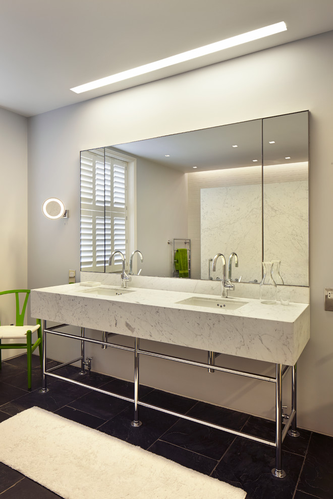 Modelo de cuarto de baño principal moderno de tamaño medio con lavabo tipo consola, encimera de mármol, bañera exenta y suelo de pizarra