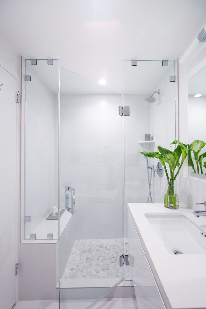 Idéer för att renovera ett mellanstort funkis badrum med dusch, med ett undermonterad handfat, släta luckor, vita skåp, bänkskiva i kvarts, en toalettstol med hel cisternkåpa, vit kakel, porslinskakel, vita väggar, klinkergolv i porslin, en dusch i en alkov, vitt golv och dusch med gångjärnsdörr