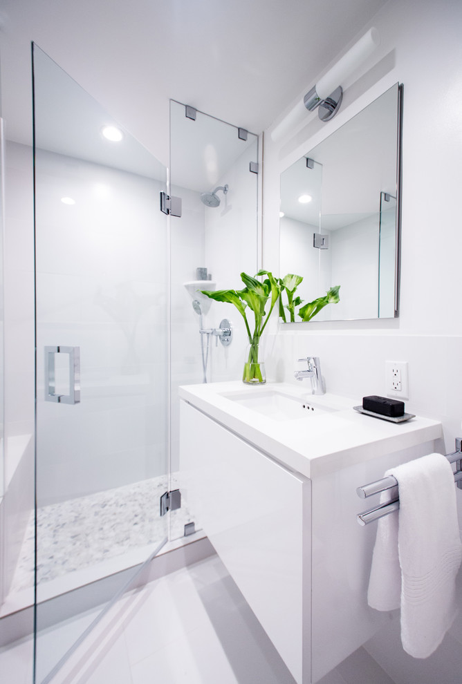 Bild på ett mellanstort funkis badrum med dusch, med ett undermonterad handfat, släta luckor, vita skåp, bänkskiva i kvarts, en toalettstol med hel cisternkåpa, vit kakel, porslinskakel, vita väggar och klinkergolv i porslin