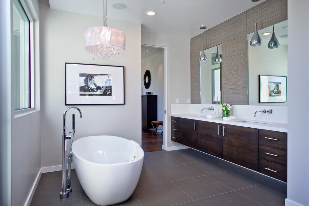 Photo of a contemporary ensuite bathroom in Los Angeles with a submerged sink, flat-panel cabinets, dark wood cabinets, a freestanding bath, grey tiles and grey walls.