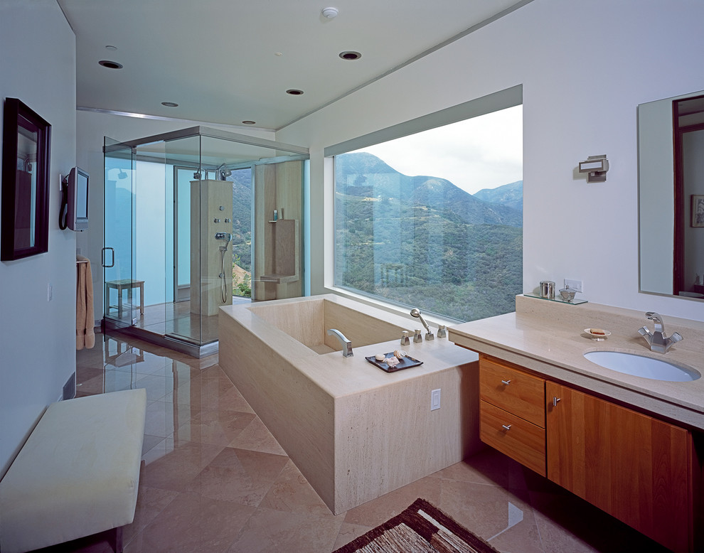 Esempio di una stanza da bagno minimal con ante lisce, ante in legno scuro, vasca freestanding, piastrelle beige, piastrelle in pietra e top in pietra calcarea