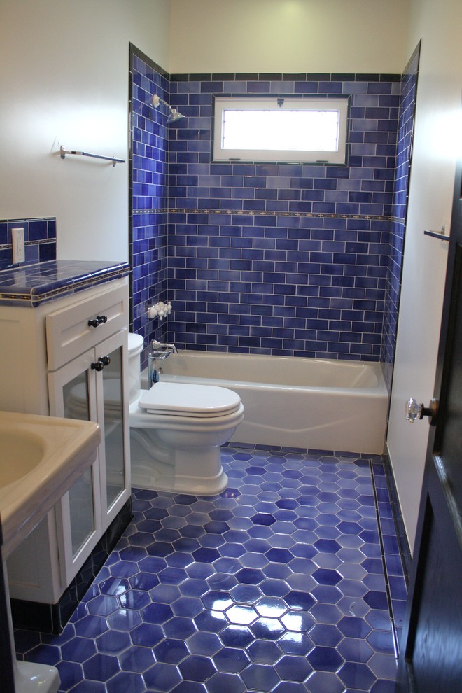 Cette photo montre une salle de bain chic de taille moyenne pour enfant avec un placard à porte affleurante, des portes de placard blanches, un plan de toilette en carrelage, WC à poser, un carrelage bleu, des carreaux de céramique, un mur blanc et un sol en carrelage de céramique.