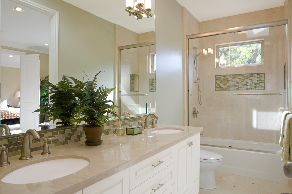 サンフランシスコにあるトランジショナルスタイルのおしゃれな浴室 (アンダーカウンター洗面器、レイズドパネル扉のキャビネット、白いキャビネット、アルコーブ型浴槽、シャワー付き浴槽	、ベージュのタイル、ベージュのカウンター) の写真