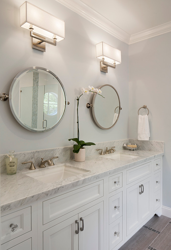 Foto de cuarto de baño tradicional renovado de tamaño medio con lavabo bajoencimera, armarios con paneles empotrados, puertas de armario blancas y paredes grises
