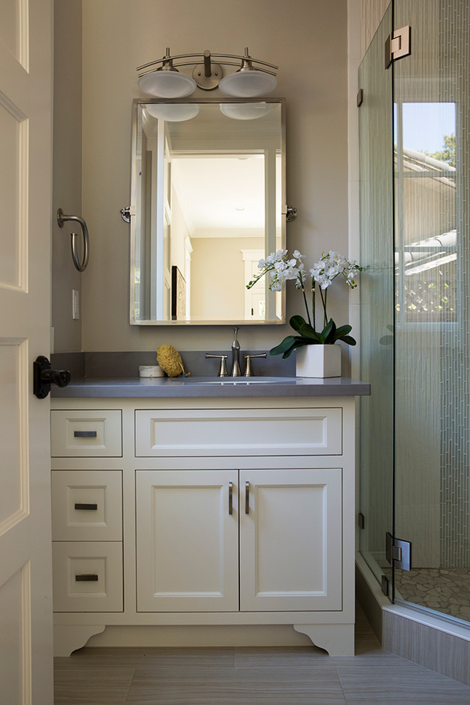 Klassisk inredning av ett grå grått badrum, med ett undermonterad handfat, luckor med infälld panel, vita skåp och beige väggar