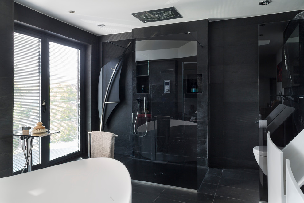 Стильный дизайн: главная ванная комната в стиле модернизм с отдельно стоящей ванной, открытым душем, инсталляцией, черной плиткой, керамической плиткой, черными стенами, консольной раковиной, черным полом и открытым душем - последний тренд