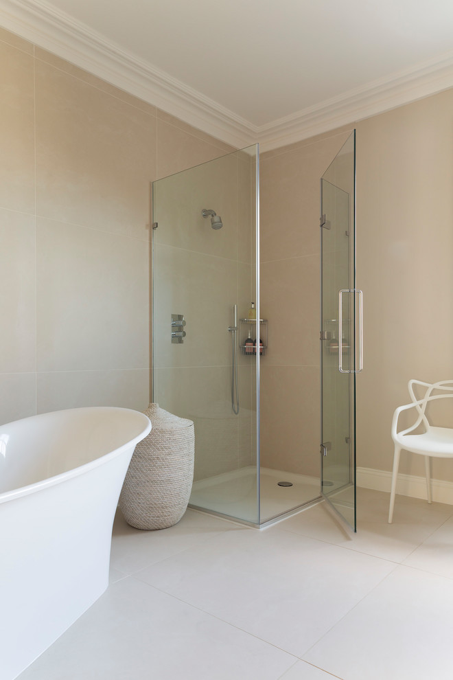 Inredning av ett klassiskt en-suite badrum, med släta luckor, beige skåp, ett fristående badkar, en hörndusch, en vägghängd toalettstol, beige kakel, keramikplattor, beige väggar och beiget golv