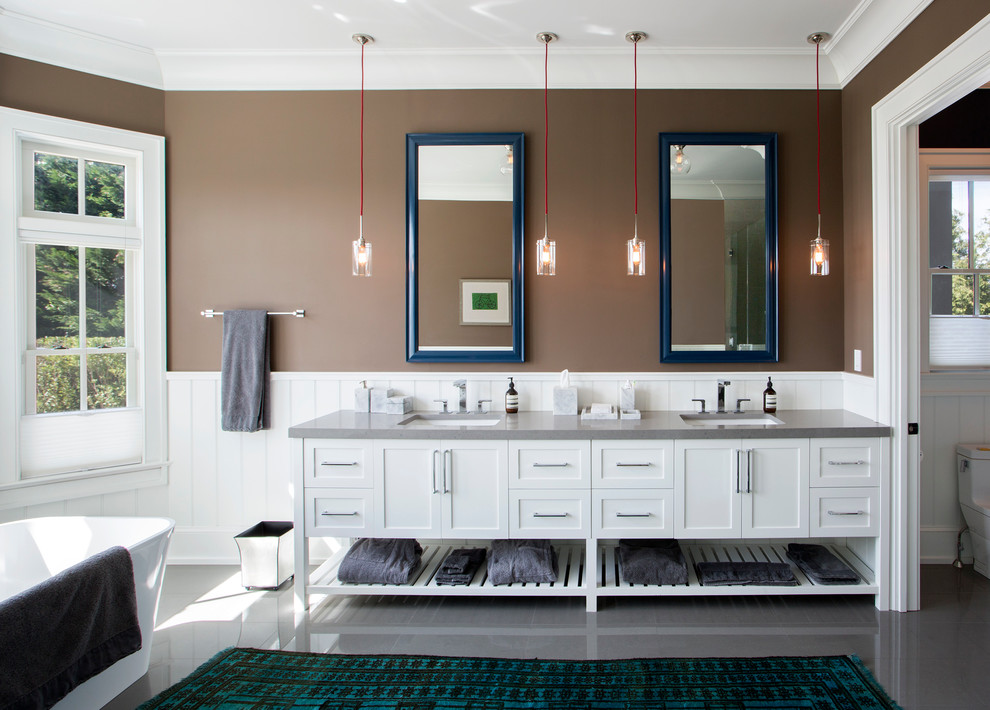 На фото: ванная комната в стиле неоклассика (современная классика) с фасадами в стиле шейкер, белыми фасадами, отдельно стоящей ванной, коричневыми стенами, полом из керамогранита, столешницей из искусственного кварца и серым полом с